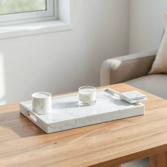 White marble serving tray and small marble accessories styled on a wooden table in a bright modern room